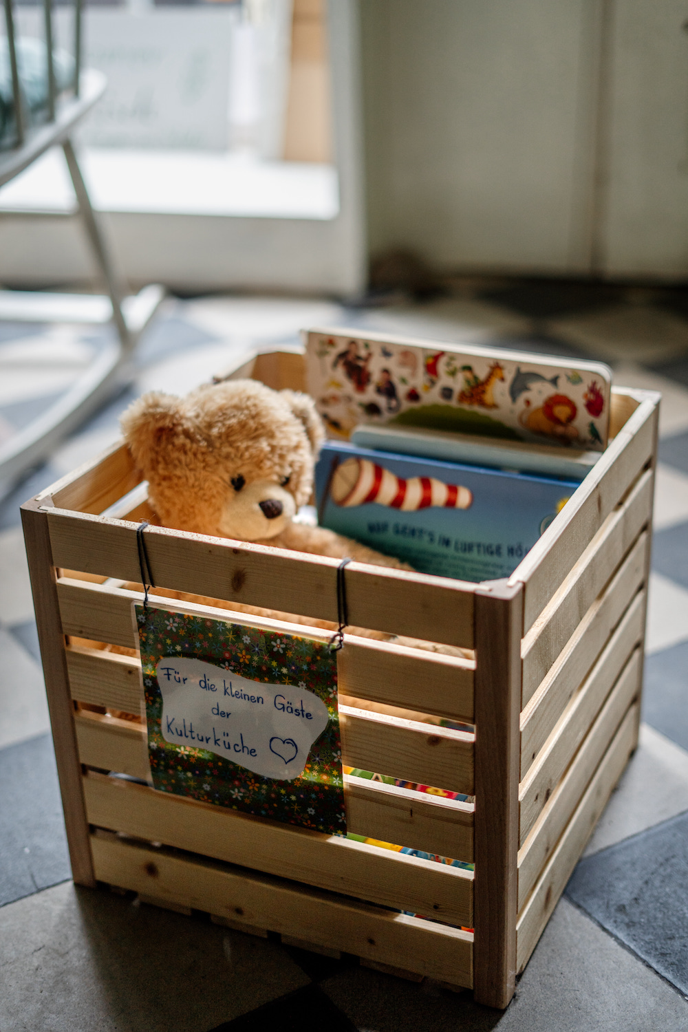 Bild von einem Holzkorb, in dem ein Kuscheltier-Bär sitzt.