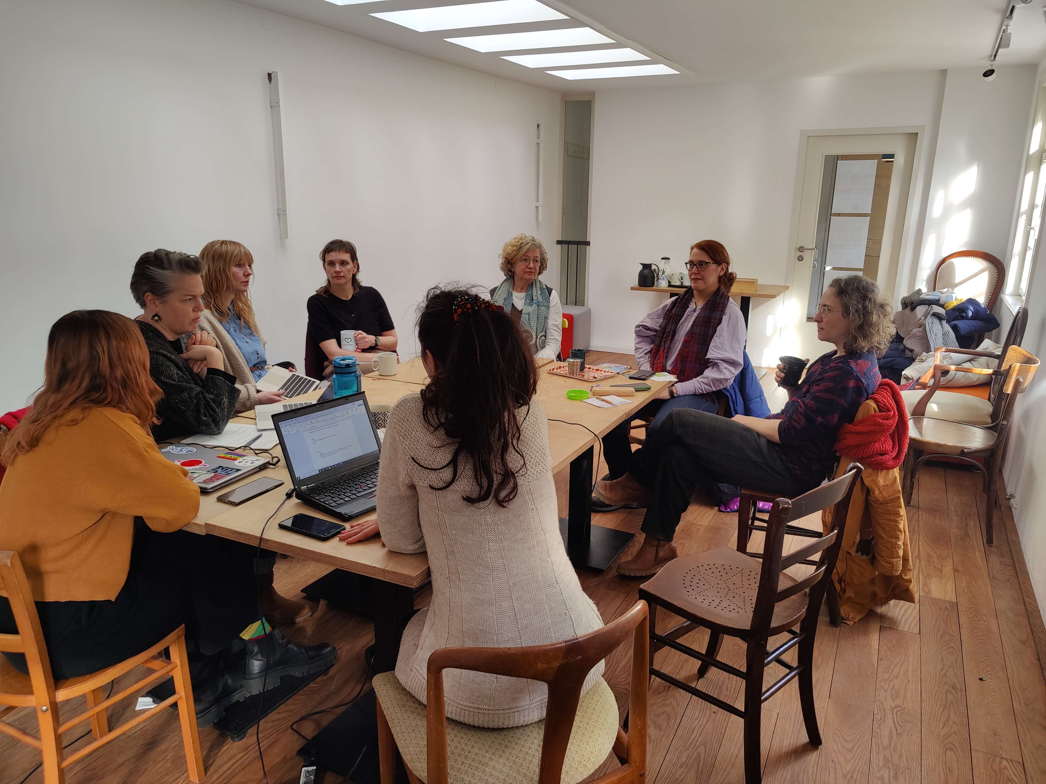 Mehrere Personen sitzen um einen Tisch und unterhalten sich