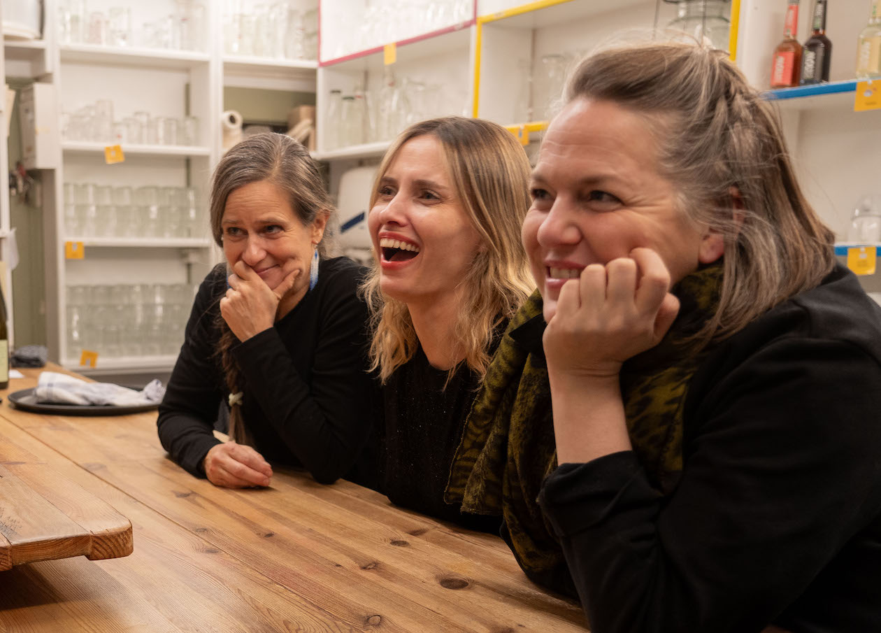 Drei Frauen, die hinter der Theke in der Kulturküche stehen und lachen.