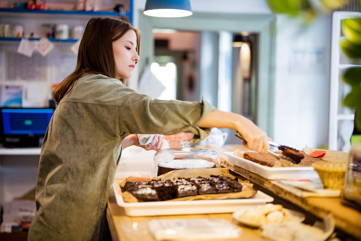 An der Theke der Kulturküche richtet eine Ehrenamtliche Kuchen vor.