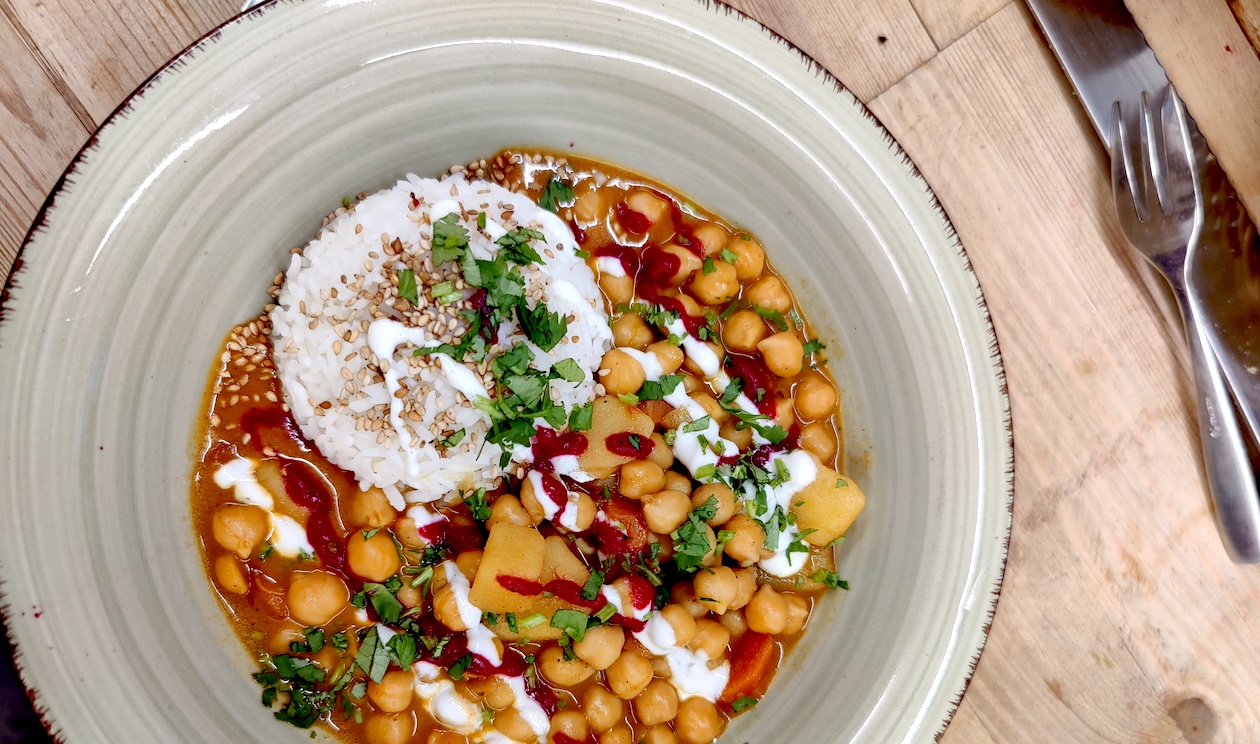 Teller mit einem Gericht aus Kichererbsen, Reise Gemüse und Topping.