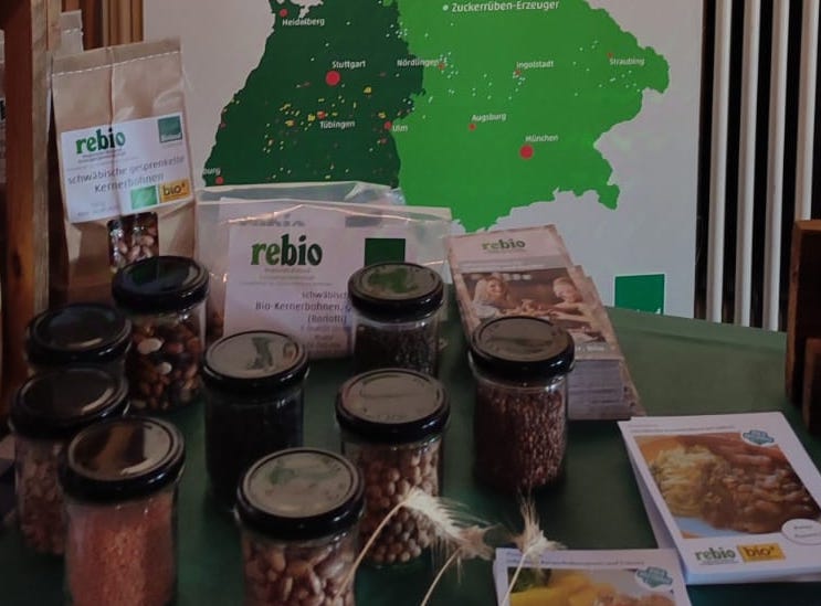 Produkte von Rebio, präsentiert auf einem Tisch. Man sieht Linsen, Bohnen, Kichererbsen und mehr.