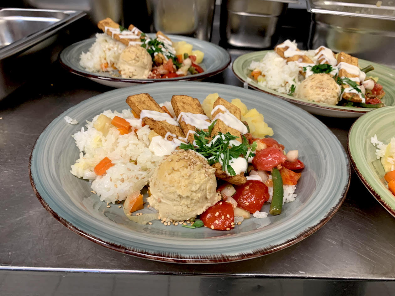 Teller mit Reis, Hummus, Gemüse und Tofu.