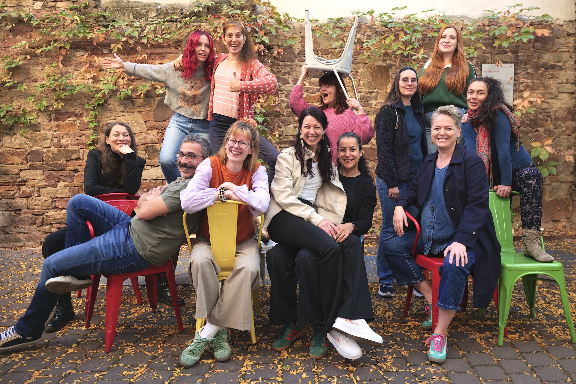 Team der Kulturküche, das auf bunten Stühlen sitzt.