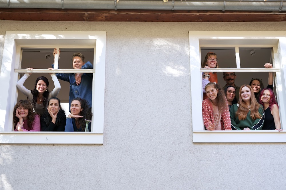 Team der Kulturküche schaut aus zwei Fenstern.